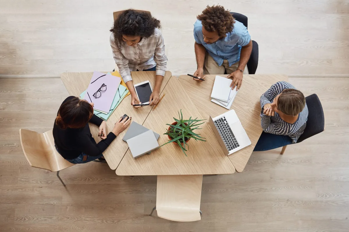 Three women and one man are seated in front of a table, deep in discussion about HR-related work.