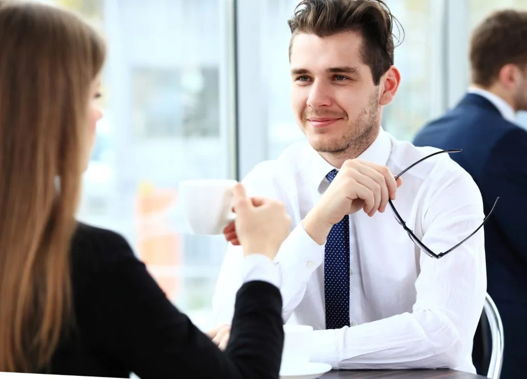 Two professionals having a discussion over coffee, emphasizing collaboration in the screening process