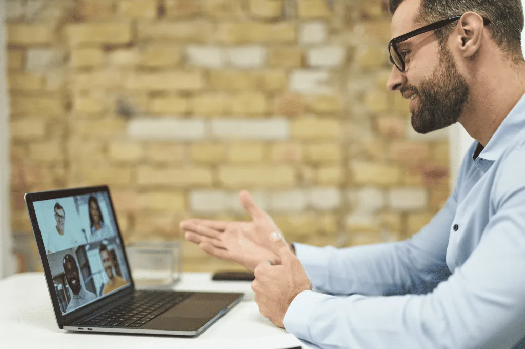 A person smiling while taking to four other people online