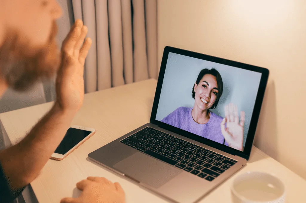 A person waving to another person on a video call