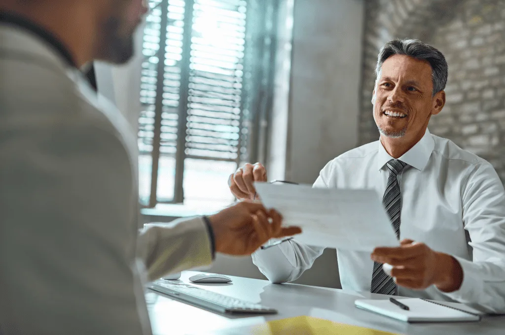 Employer talking with candidate taking his resume during job interview office