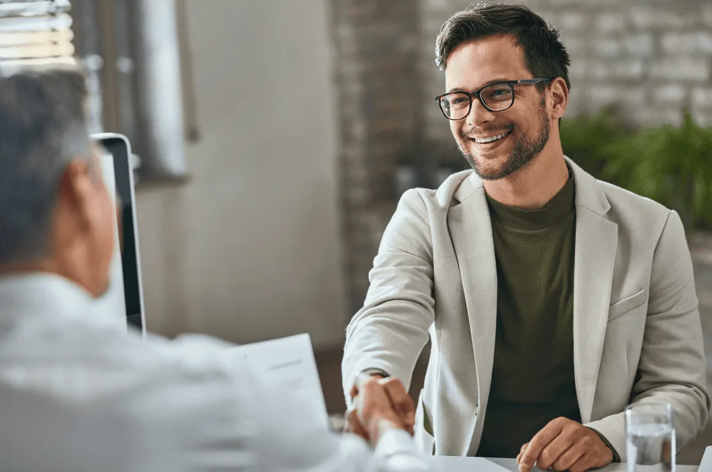 Happy candidate handshaking with manager after successful job interview office