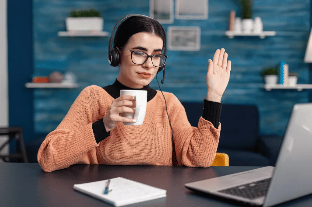 Individual holding a cup of coffee during an online meeting