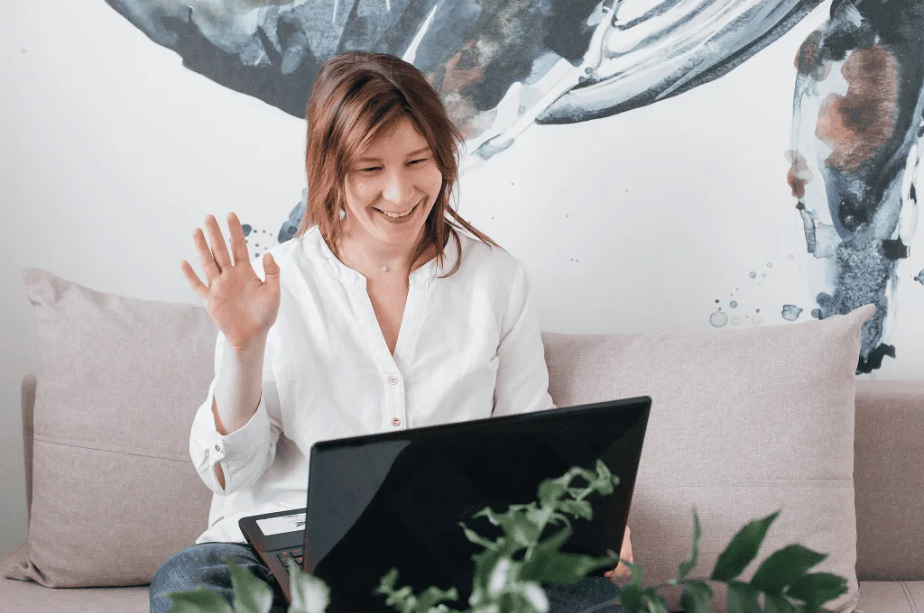 Woman waving to someone while talking to them on a video call
