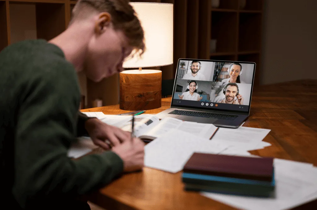 Young man noting something down during an online video conferenece
