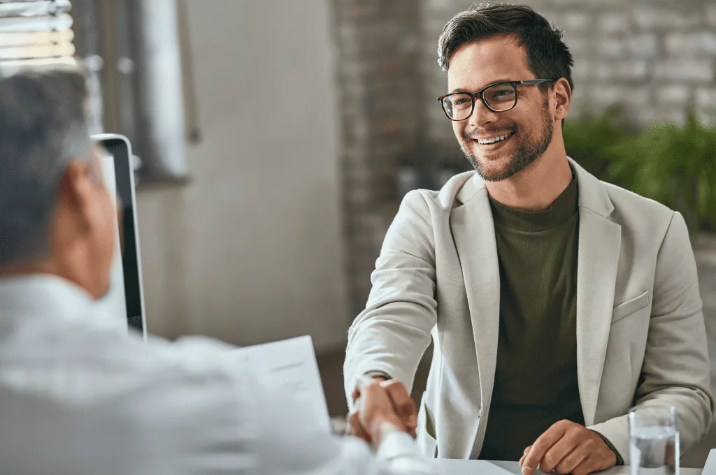 Happy male candidate handshaking with manager after successful job interview in the office
