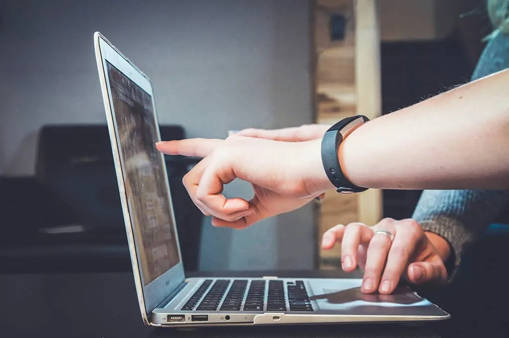 A close-up of a laptop with the hands of workers typing, highlighting the hands-on implementation of email automation tools in HR practices