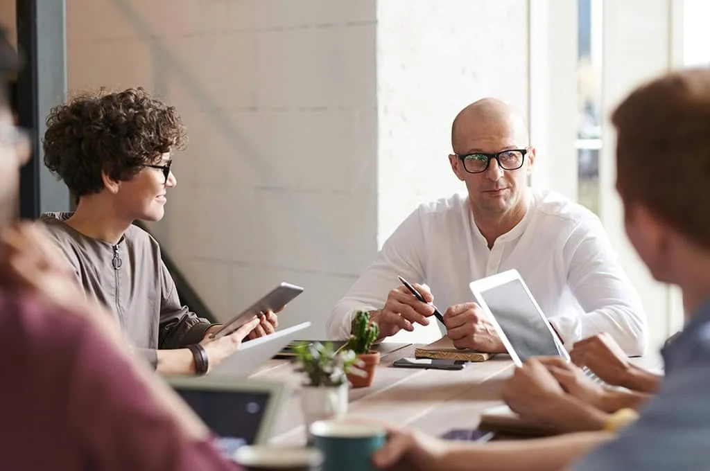 HR team in a meeting discussing compliance, seated around a conference table with documents and laptops